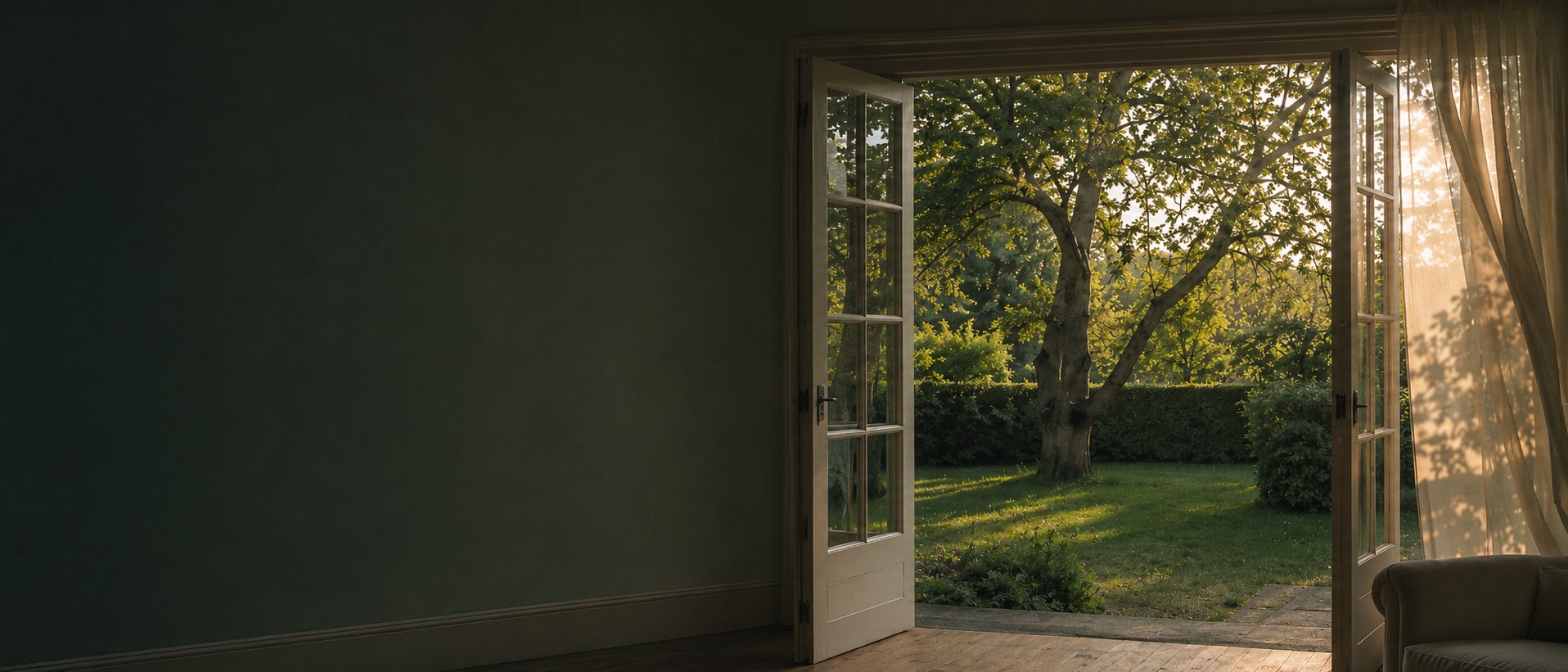 Blick durch geöffnete Flügeltüren in einen Garten am Abend